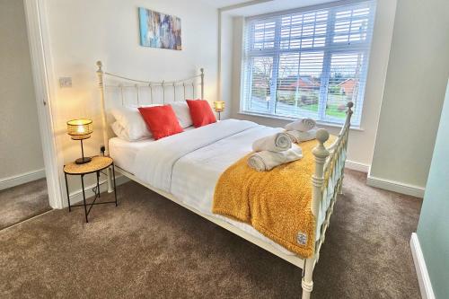 a bedroom with a bed with red pillows and a window at Cosy yet spacious, 3BR, Parking, Village Location in Oswestry