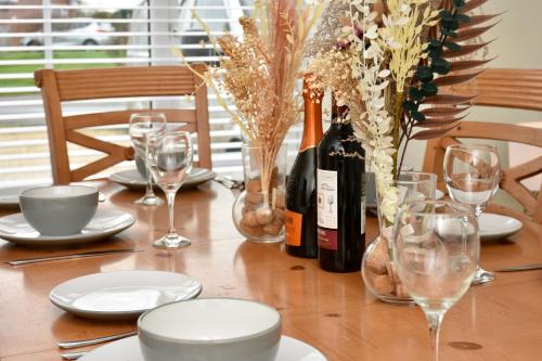 a wooden table with a bottle of wine and glasses at Cosy yet spacious, 3BR, Parking, Village Location in Oswestry