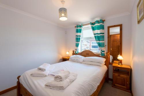 1 dormitorio con 1 cama con toallas en Tregurrian Villas, en Newquay