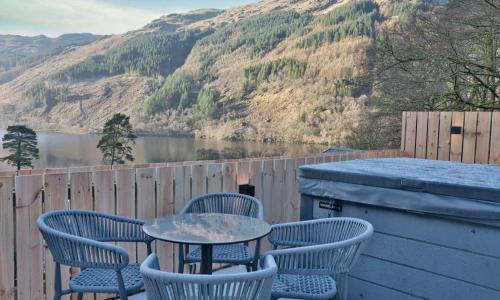 a table and chairs on a deck with a view of a lake at Loch Eck Holiday Park in Coirantee