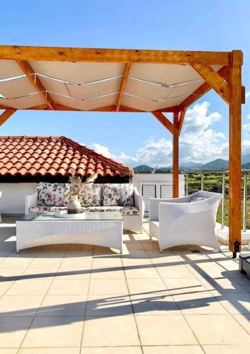 a patio with white furniture under a roof at Boho Bay Apartment in Akanthou
