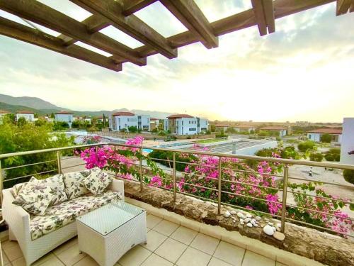 a couch sitting on a balcony with pink flowers at Boho Bay Apartment in Akanthou