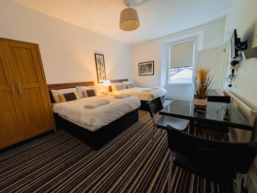 ウェストン・スーパー・メアにあるBay & Harbour Holiday Apartments & rooms onlyのベッド2台とデスクが備わるホテルルームです。