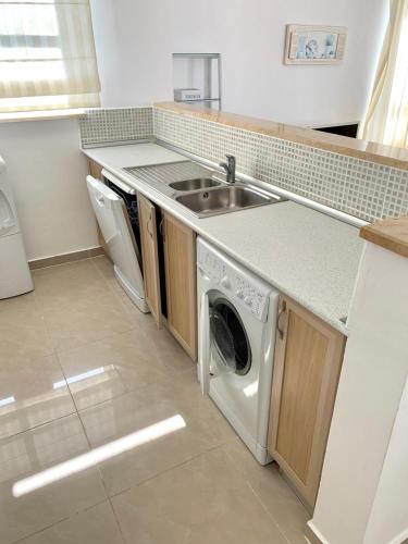 a kitchen with a sink and a washing machine at Boho Bay Apartment in Akanthou