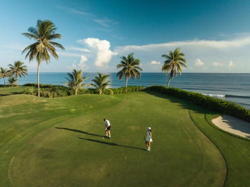 two people playing golf on a golf course near the ocean at Jewel Grande Montego Bay Resort and Spa in Montego Bay