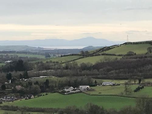 uma vista para um campo verde com casas e colinas em Stunning Shepherds Hut rural bliss Dumfries em Dumfries