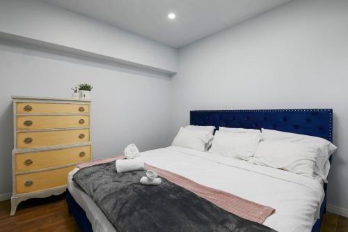 a bedroom with a bed with a blue headboard and a dresser at The Nordic 2BR Chalet by Instant Suites - 5 min to Tremblant Village in Mont-Tremblant