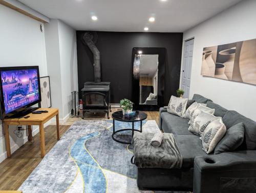 a living room with a couch and a tv at The Nordic 2BR Chalet by Instant Suites - 5 min to Tremblant Village in Mont-Tremblant