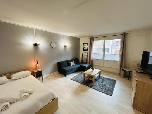een slaapkamer met een bed, een bank en een tv bij La Suite Victor Hugo - Centre-ville - Taittinger in Reims