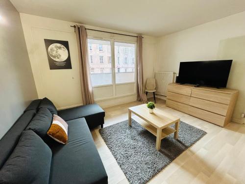 een woonkamer met een blauwe bank en een televisie bij La Suite Victor Hugo - Centre-ville - Taittinger in Reims