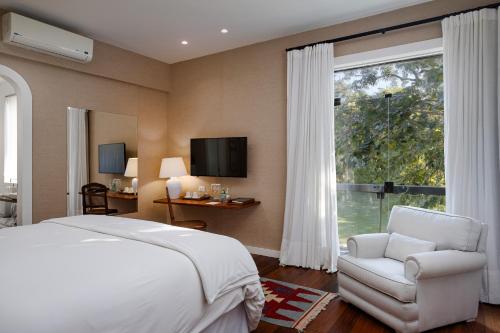 a bedroom with a bed and a chair and a window at Vila Santa Teresa in Rio de Janeiro