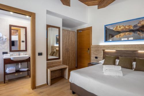 a bedroom with a bed and a sink and a mirror at Park Hotel in Folgarida
