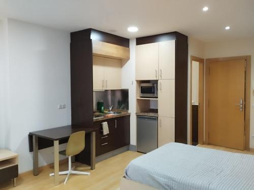 a bedroom with a bed and a desk and a kitchen at Estudio Céntrico A1 in Oviedo