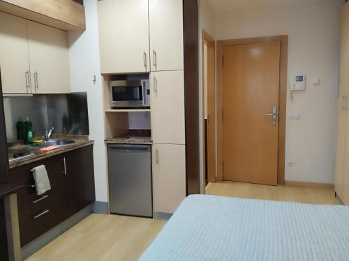 a small kitchen with a bed and a microwave at Estudio Céntrico A1 in Oviedo