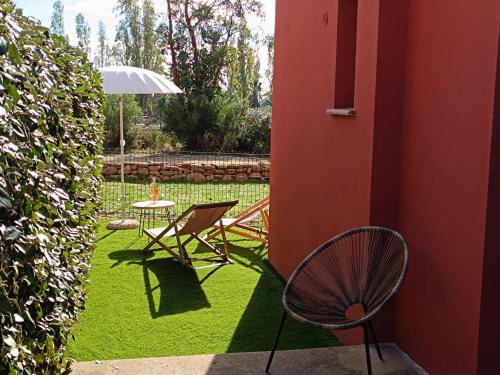 a patio with a table and a chair and an umbrella at T3 Picchiarini, Clim, piscines, resto, 5' plages in Lecci