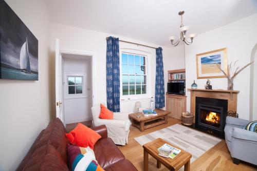 a living room with a couch and a fireplace at Fort Victoria Cottages - Sea View Cottage in Yarmouth