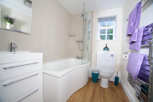a white bathroom with a tub and a toilet at Fort Victoria Cottages - Sea View Cottage in Yarmouth