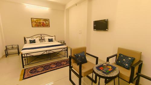- une chambre avec un lit, deux chaises et une télévision dans l'établissement Hotel Amazing Udaipur (Prime inn ), à Udaipur
