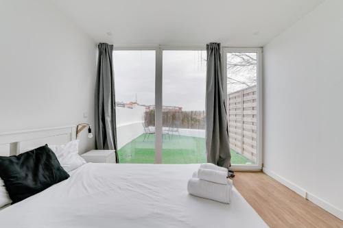 a bedroom with a white bed and a large window at By the Palace - Ajuda Apartments in Lisbon
