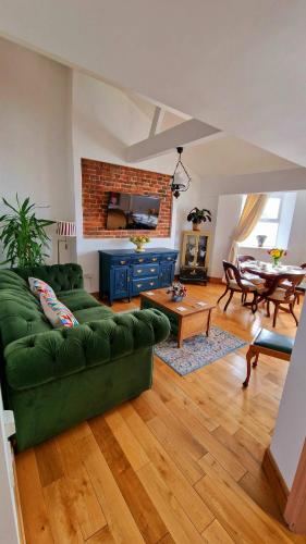 a living room with a green couch and a table at The Three Musketeers, Aramis in Eastbourne