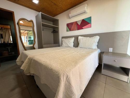 - une chambre avec un lit et une couette blanche dans l'établissement Bangalô de luxo beira mar com piscina privativa na desnubrante praia de Barrinha, à Barrinha
