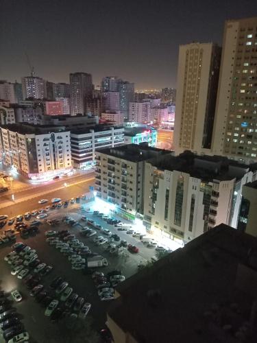 a city at night with cars parked in a parking lot at FEMALE SHARING BED SPACE near CORNICHE in Sharjah