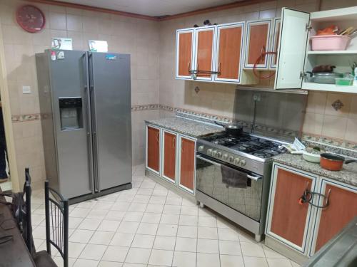 a kitchen with stainless steel appliances and brown cabinets at SHARING BED SPACE FOR MALE near DUBAI BUS STOP in Sharjah