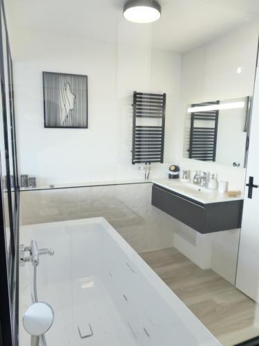 a white bathroom with a tub and a sink at La Cité des Coeurs LU Parking inclus in Nantes