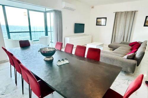 a living room with a table and red chairs at XL Seafront Home in Sliema in Sliema