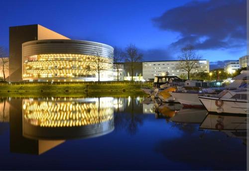 un bâtiment avec des bateaux dans l'eau la nuit dans l'établissement La Cité des Coeurs LU Parking inclus, à Nantes