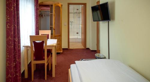 a room with a bed and a table and a television at Hotel Bisenius in Traben-Trarbach