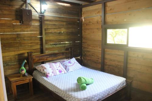 a bedroom with a bed in a wooden cabin at Rancho Los Duendes in Turrialba