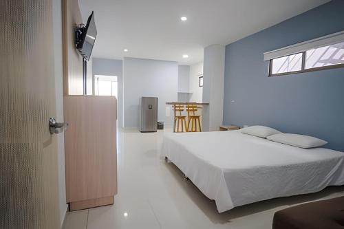 1 dormitorio con cama blanca y pared azul en Lagos Apartaestudios Apartamento, en Barranquilla