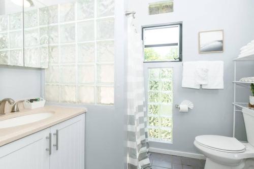 a white bathroom with a toilet and a sink at Island Oasis: Beach & Views in Enighed