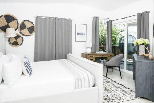 ein weißes Schlafzimmer mit einem weißen Bett und einem Schreibtisch in der Unterkunft Island Oasis: Beach & Views in Enighed