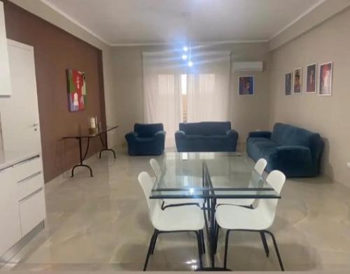 sala de estar con mesa de cristal y sillas blancas en Marconi Rooms and Apartaments, en Campobello di Licata