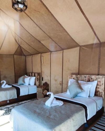 two beds in a room with two swans on them at Sunset Camp Merzouga in Merzouga
