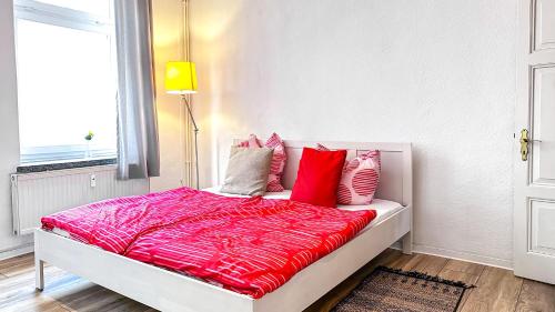 um quarto com uma cama com lençóis vermelhos e uma janela em gemütliche Ferienwohnung mit Gartennutzung em Schwerin