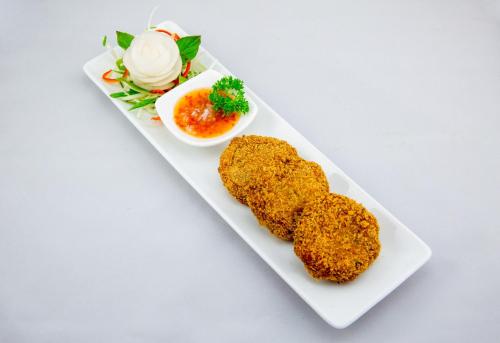 a white plate with two fried food on it at Vacation Boutique Hotel in Phnom Penh
