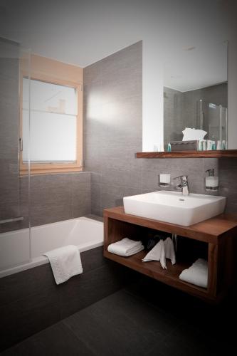 a bathroom with a white sink and a bath tub at Chalet Nepomuk in Zermatt