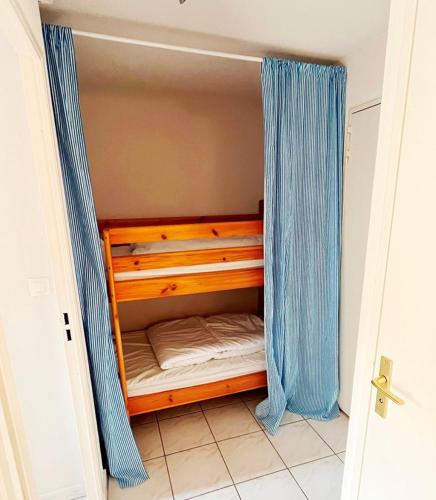 - un petit lit dans une chambre dotée de rideaux bleus dans l'établissement Joli 2 pièces cabine climatisé dans une résidence avec piscine, à Cavalaire-sur-Mer
