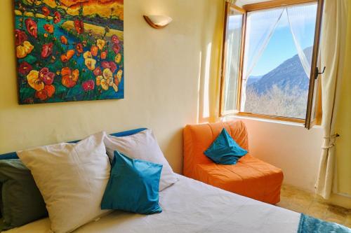 - une chambre avec un lit, une chaise orange et une fenêtre dans l'établissement Château Cottage -Vue sur le Verdon et tranquillité, à Castellane
