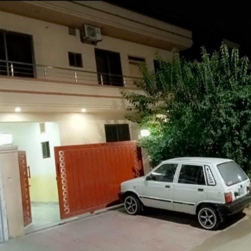 a white car parked in front of a building at Green lodge Guest House Islamabad in Islamabad