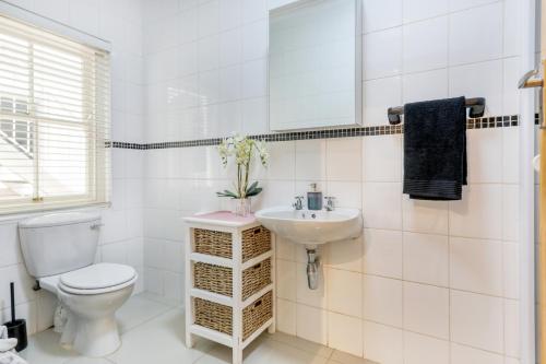 a white bathroom with a toilet and a sink at Modern victorian city house, work, live, play! in Cape Town