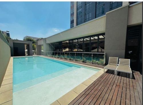 Johannesburg的住宿－NEW Luxury Hotel Suite Sandton City，一座带两把椅子的游泳池以及一座建筑
