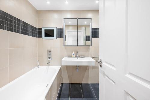 a bathroom with a sink and a tub and a mirror at Casa Italia near Kensington High Street - Wifi & Washing Machine in London