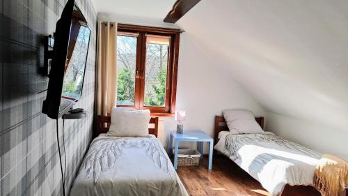 Duas camas num pequeno quarto com uma janela em Apartament Pod Lipami em Suwałki