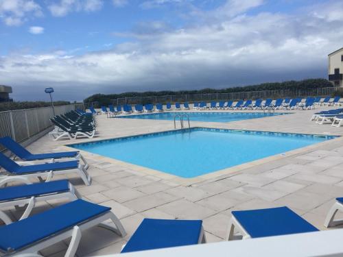 - une piscine avec des chaises bleues et un bouquet d'équipements dans l'établissement T2 DIRECT PLAGE LACANAU OCEAN 2 PISCINES PARKING TERRASSE 9m2, à Lacanau-Océan