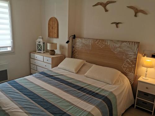 1 dormitorio con 1 cama con cabecero de madera en L Etoile de Mer - Piscine chauffee, en Saint-Vincent-sur-Jard