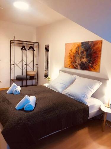 a bedroom with a large bed with blue slippers on it at Servus Apartments Stadt Blick in Passau